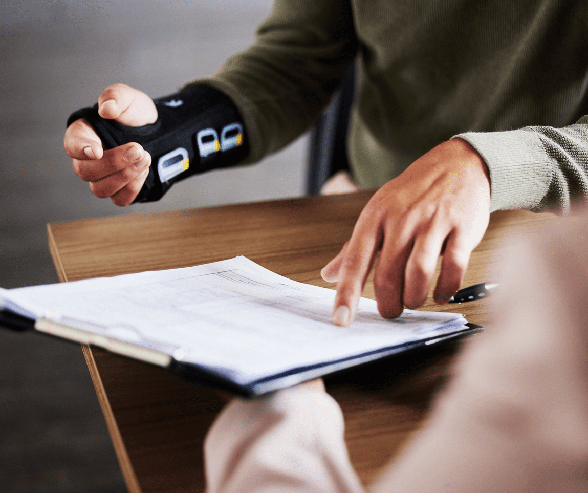 Person pointing at documents on a table.